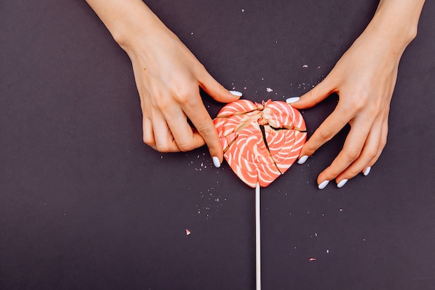 Female hands are trying to collect broken candy in the form of a heart