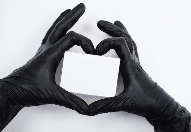 Female hands in black gloves make a heart sign around the cream in the package Skin care concept