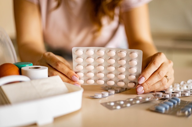 Женские руки блистерная упаковка таблеток первая аптечка организация хранения витаминное обезболивающее лекарство