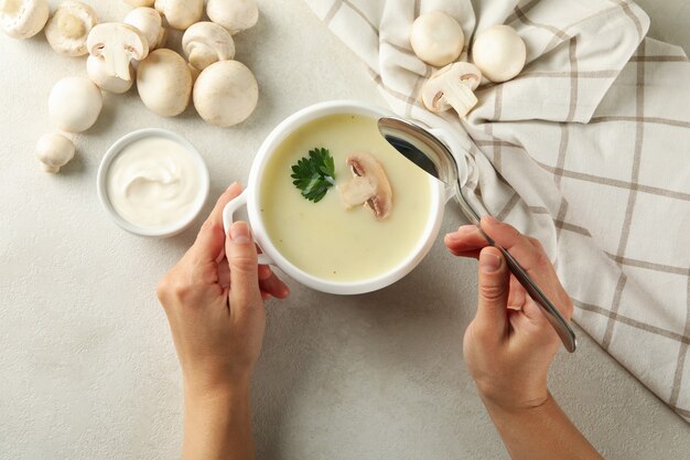 Female hands and bowl of tasty mushroom soup, top view