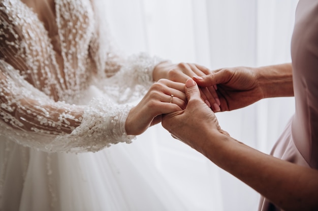 家の中の結婚式の日に花嫁と母親の女性の手