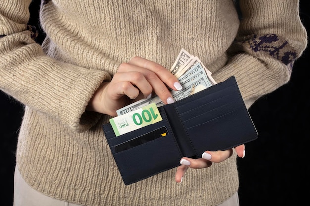 In female hands a brown wallet with euros and dollars