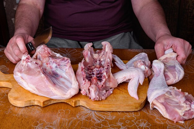 Foto le mani femminili scolpiscono un'intera carcassa di pollo su una tavola di legno