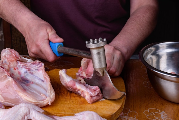 Foto le mani femminili scolpiscono un'intera carcassa di pollo su una tavola di legno