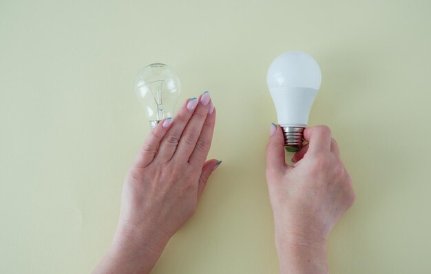 Женские руки выбирают светодиодную лампочку вместо лампочки накаливания Концепция экономии энергии