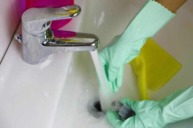 Female hands cleaning water tap in the bathroom.