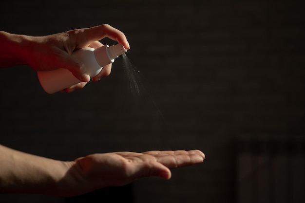 Female hands closeup with antiseptic spray A woman for the prevention of coronavirus sprays an antibacterial agent in the palm of her hand