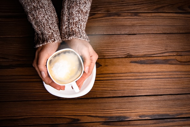 Female hands and coffee on wooden background