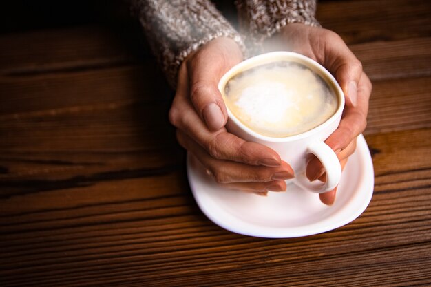 Female hands and coffee on wooden background