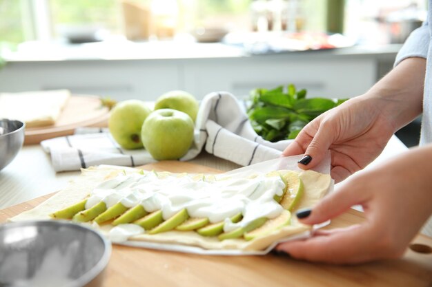 Female hands cooking apple dessert in kitchen