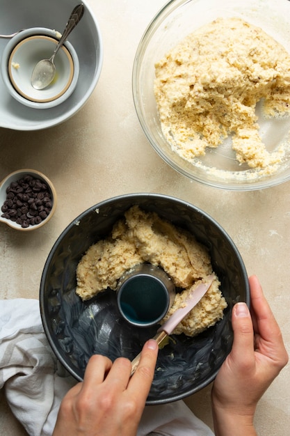 Female hands cooking bundt cake in bundt tin metal pan, raw dough for cake