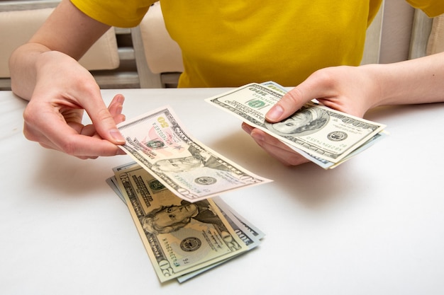 Female hands count a bundle with dollars, shift from one side to another, the concept of financial independence.