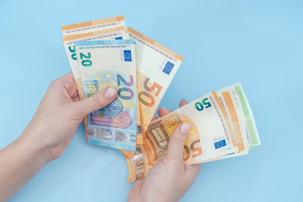 female hands counting stack of euro banknotes on blue background money business finance