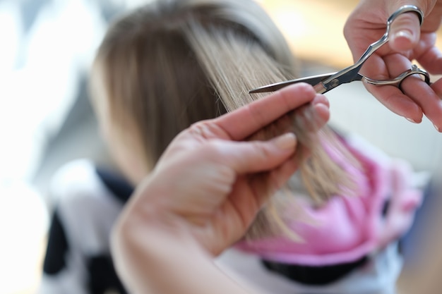 Female hands cut the hair of a woman with scissors
