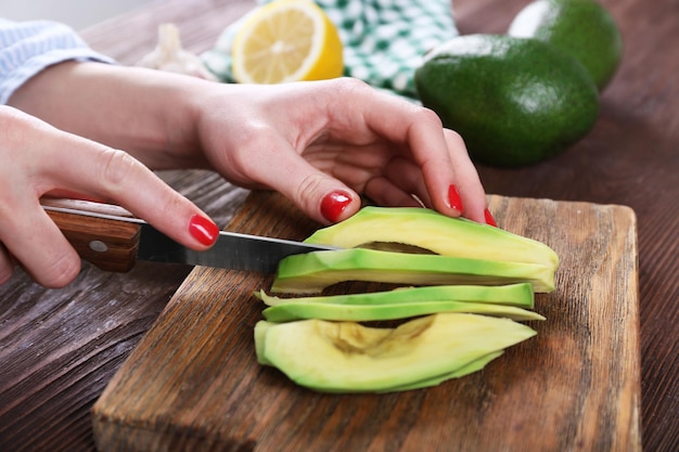 Photo female hands cutting avocado into slices close up