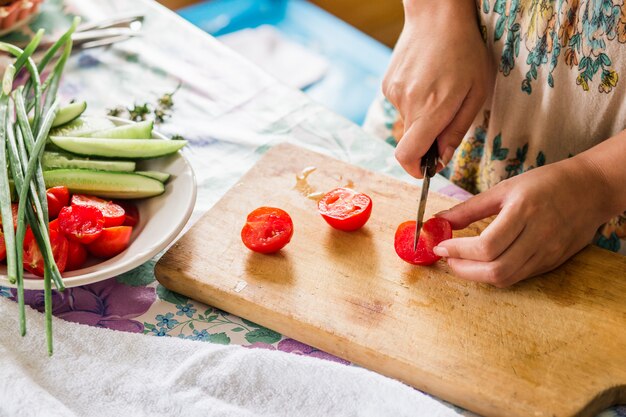 Mani femminili che tagliano le verdure per insalata, alla cucina