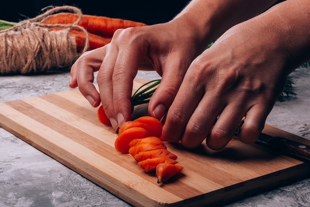 Женские руки разбавляют ломтиками свежей моркови