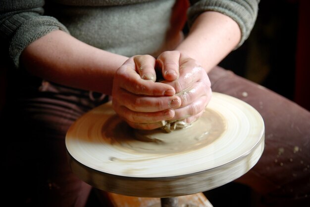 Female hands forming clay pot on the pottery wheel