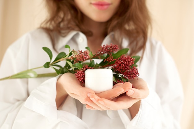 Female hands gently hold white jar of cream. mock up cosmetics concept