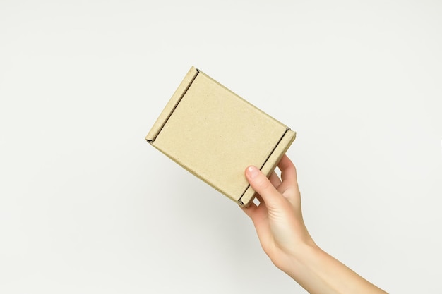 Photo female hands give a small brown cardboard box on a white background delivery concept