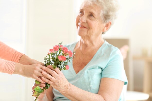 Female Hands Giving Flowers To Old Woman