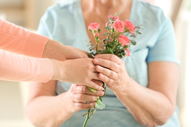 Female Hands Giving Flowers To Old Woman