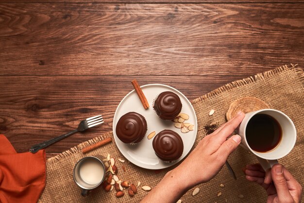 Female hands grabbing a coffee cup from a table with chocolate desserts