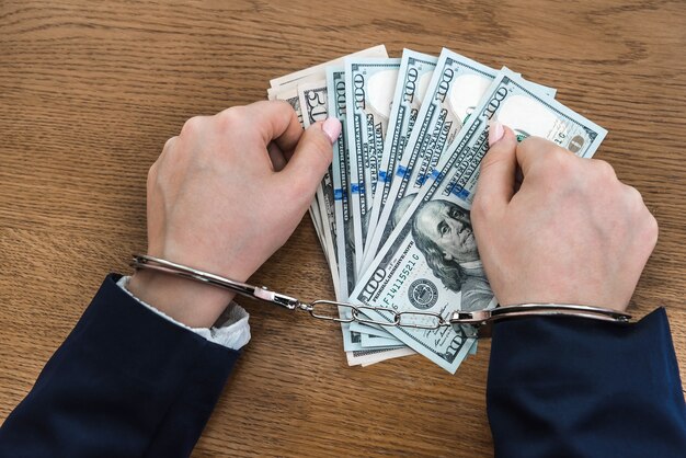 Female hands in handcuffs on dollar bribe