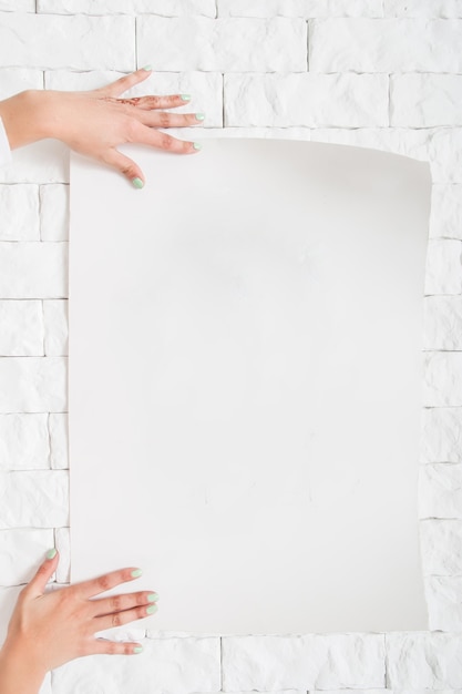 Female hands hanging blank poster to wall