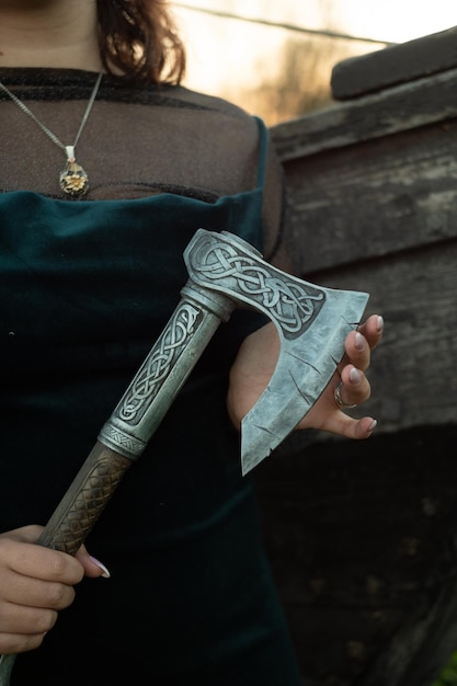 Фото Женские руки держат небольшой топор с резным узором из игры assassin's creed.