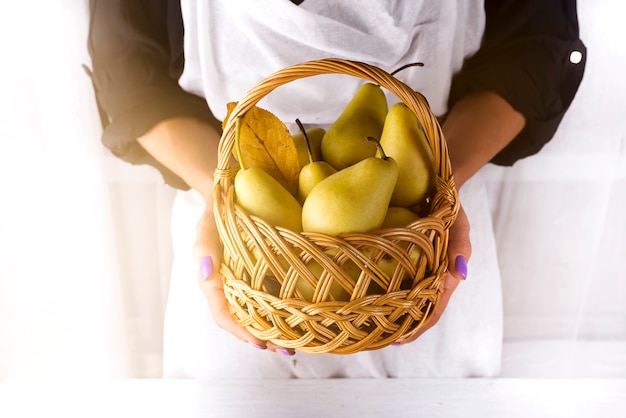 Female hands hold a basket with pears