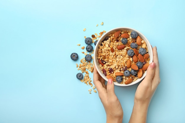 Mani femminili tengono ciotola con muesli isolato