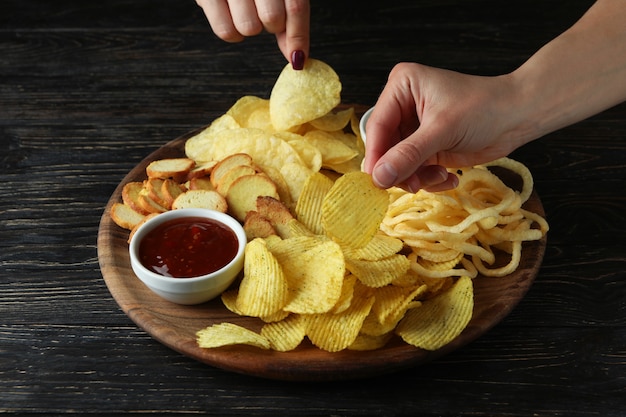 Female hands hold chips over the tray with chips, close up