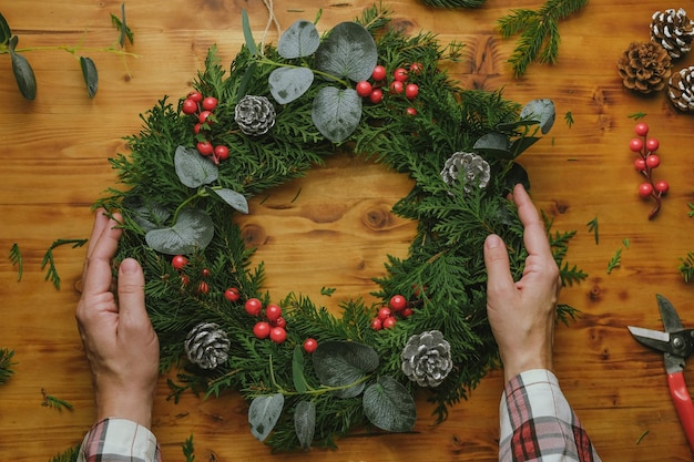 Female hands hold Christmas wreath DIY Xmas home decoration