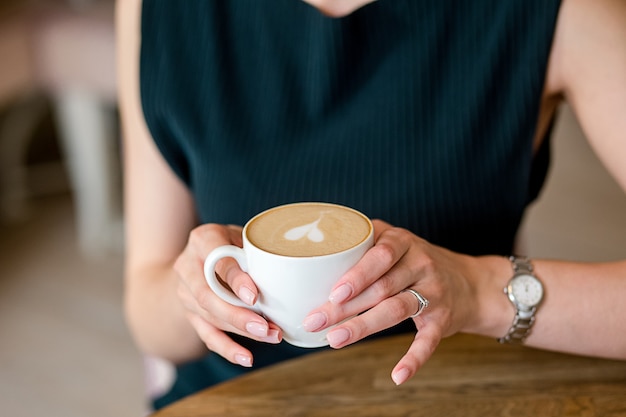 女性の手はコーヒーを保持します