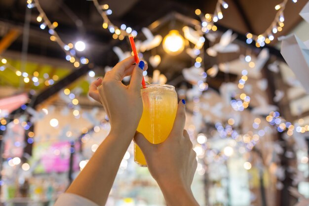 Female hands hold a glass against the backdrop of the new year tree and garlands