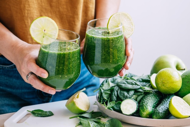 Female hands hold a glass of freshly made green smoothie selective focus copy space Vegetarianism