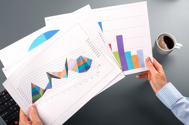 Female hands hold graphic charts. Female employee&amp;#39;s hands holding charts. Comparing levels of productivity. It was a difficult year.