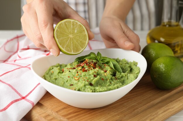 Female hands hold lime and bowl with guacamole