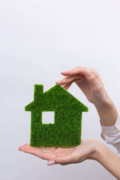 Female hands hold a model of a green house closeup Sale of ecological real estate of the future