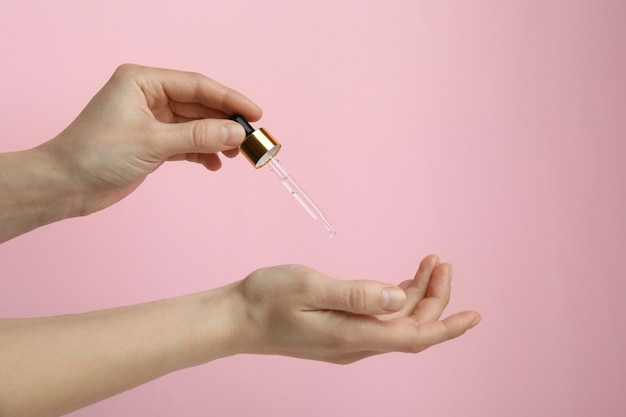 Female hands hold pipette with pine oil on pink