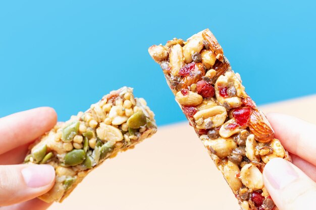 Photo female hands hold a protein bars on a blue and brown background