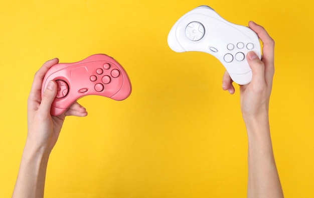 Female hands hold retro gempads on yellow background Gaming concept