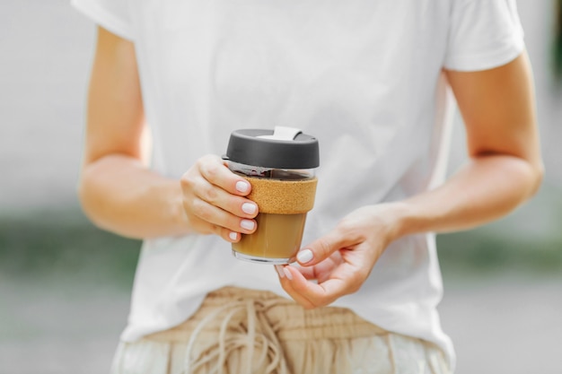 女性の手は再利用可能なコーヒーマグを持っています。持続可能なライフスタイル。環境にやさしいコンセプト。