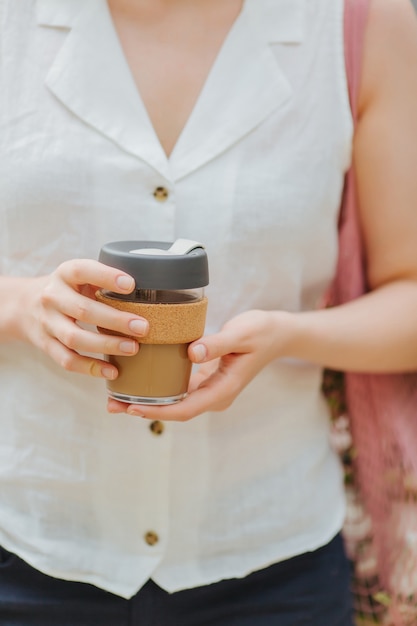 女性の手は再利用可能なコーヒーマグを持っています。持続可能なライフスタイル。環境にやさしいコンセプト。