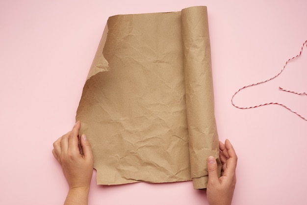 Photo female hands hold a roll of brown paper