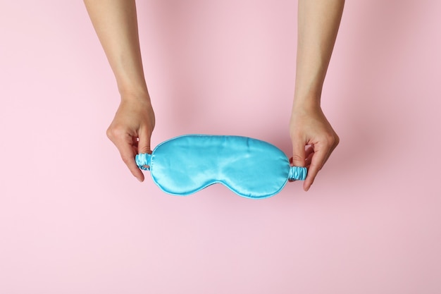 Female hands hold sleep mask on pink