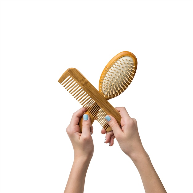 Photo female hands hold two wooden combs isolated on a white surface