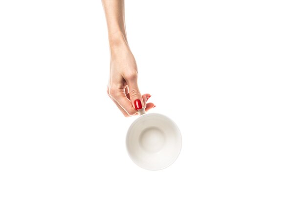 Female hands hold a white ceramic cup on white background Female hands with fresh red manicure Isolated on white background