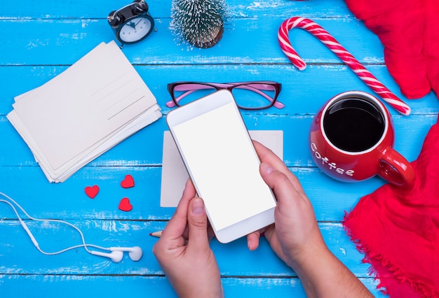 Female hands hold a white smartphone with a blank screen 